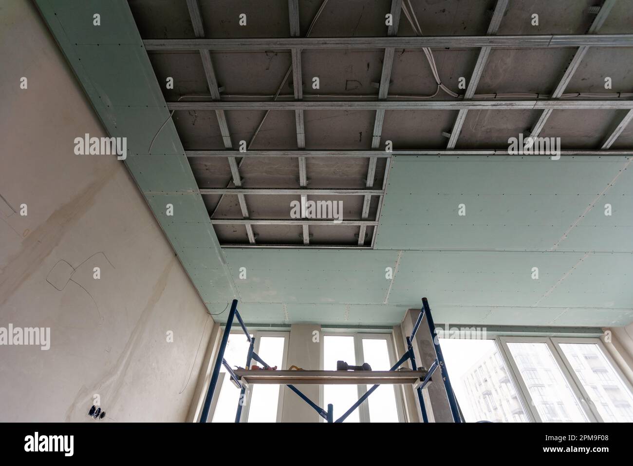 Installation au plafond avec des techniciens experts dans la pièce en cours de construction Banque D'Images