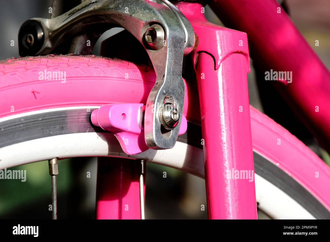 gros plan de la fourche de vélo de course de style vintage et du frein  avant. pneu et plaquettes de frein en caoutchouc rose. rayons métalliques.  concept de transport et de technologie