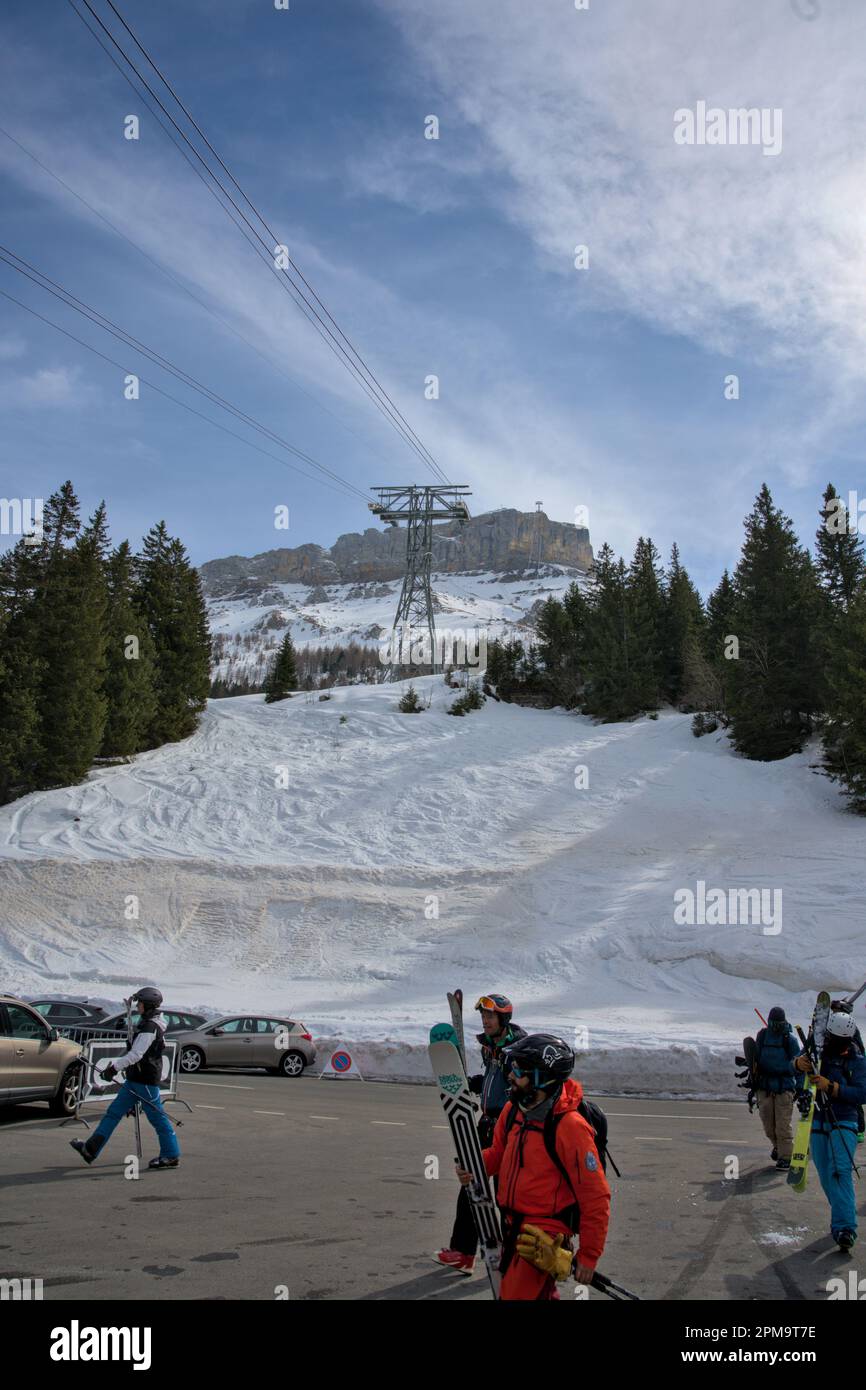 Groupe de skieurs traversant la rue et le parking pour atteindre le téléphérique qui les rerendra au sommet Banque D'Images