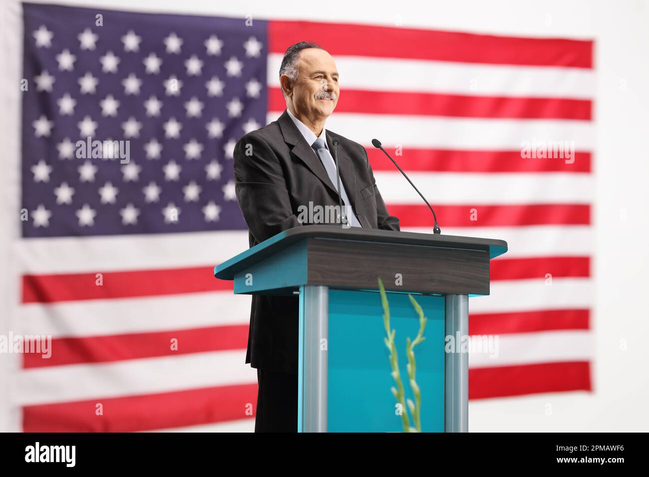 Homme politique américain prononcera un discours sur un podium en souriant avec un drapeau en arrière-plan Banque D'Images