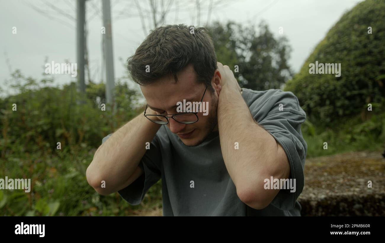 Un jeune homme avec des lunettes se bat dans la douleur, luttant contre un début soudain de problèmes de santé Banque D'Images