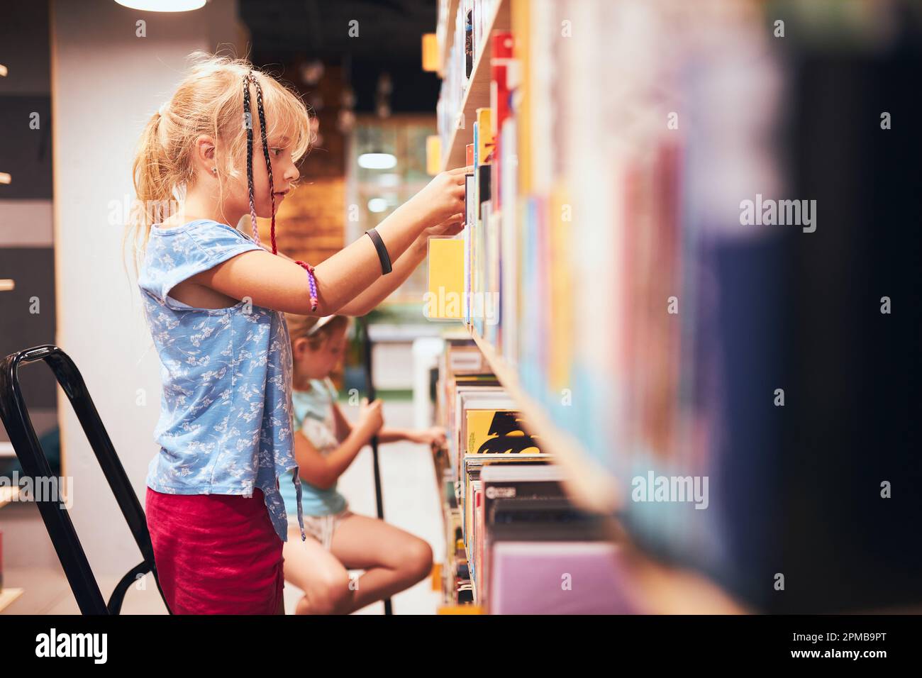 Écolières à la recherche de livres dans la bibliothèque de l'école. Étudiants choisissant des livres. L'éducation élémentaire. Faire des devoirs. Apprendre à partir de livres. Retour à l'école Banque D'Images