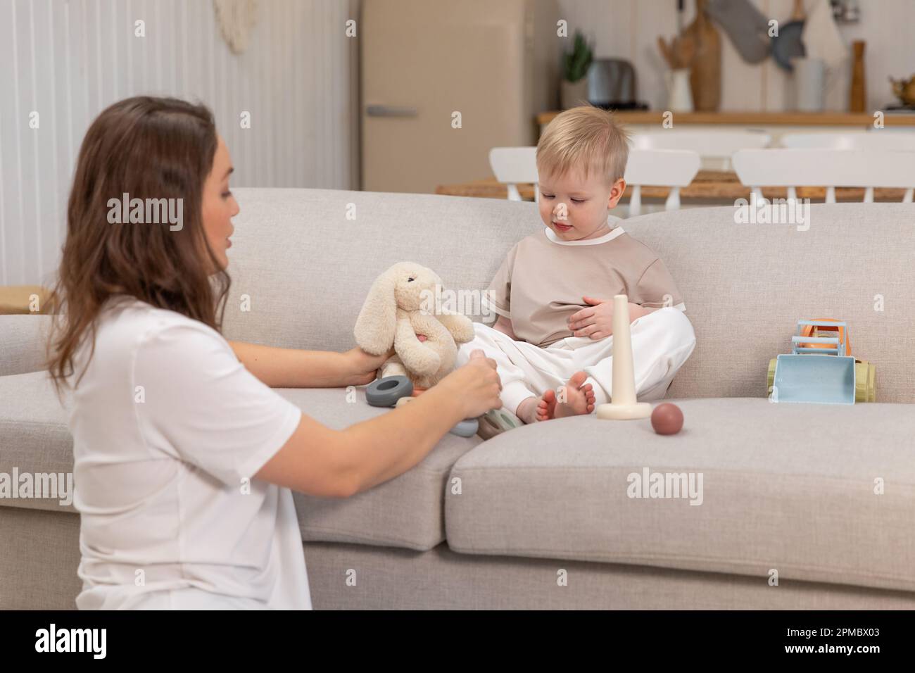 Bonne famille a la maison. Mere et bebe garcon jouant avec des jouets dans le canape a la maison a l interieur. Petit enfant et nounou de baby sitter s amuser ensemble. Jeune femme maman