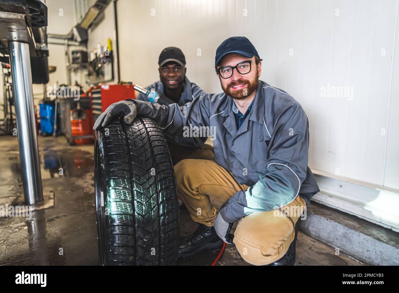 deux mécaniciens se préparer à changer une roue sur la voiture, atelier de réparation de voiture. Photo de haute qualité Banque D'Images