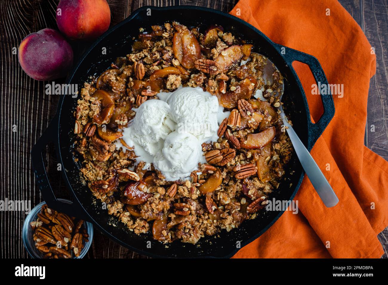 Pécan Bourbon croustillant recouvert de glace vanille : dessert fait avec des pêches, du bourbon et des pacanes dans une poêle en fonte Banque D'Images