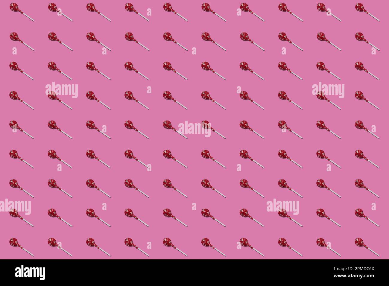 Sucettes Lollipop avec enveloppeurs rouges dans un motif répétitif sur un fond rose sans couture Banque D'Images