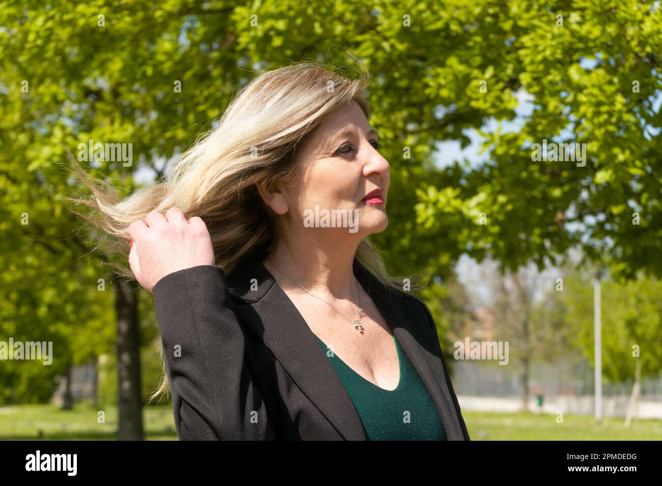 Bonne femme blonde mûre marchant dans le parc Banque D'Images