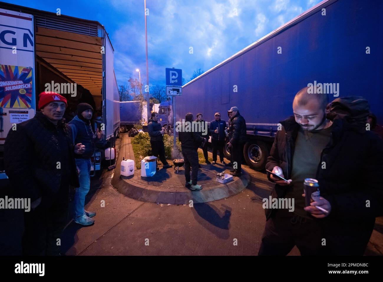 Weiterstadt, Allemagne. 12th avril 2023. Les chauffeurs routiers se tiennent autour d'un grill lors d'une grève des chauffeurs routiers d'une société logistique polonaise dans la zone de service de Gräfenhausen West dans la soirée. Les chauffeurs routiers exigent des salaires exceptionnels de leur employeur. (À dpa-KORR 'le contrat est un contrat - les chauffeurs en grève veulent voir de l'argent pour le travail') Credit: Sebastian Christoph Gollnow/dpa/Alay Live News Banque D'Images