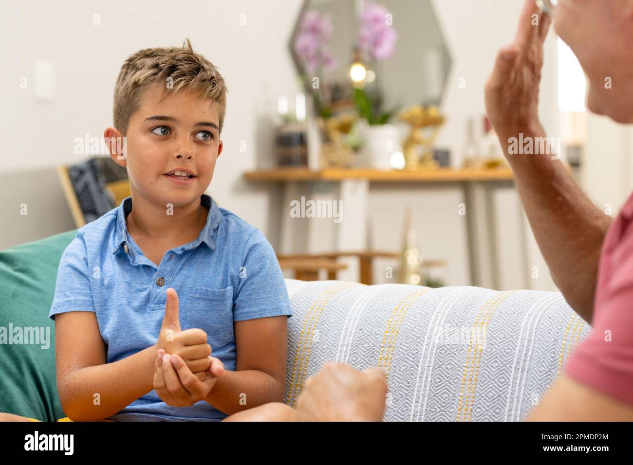 Grand-père caucasien communiquant avec le petit-fils en langue des signes tout en étant assis sur un canapé Banque D'Images