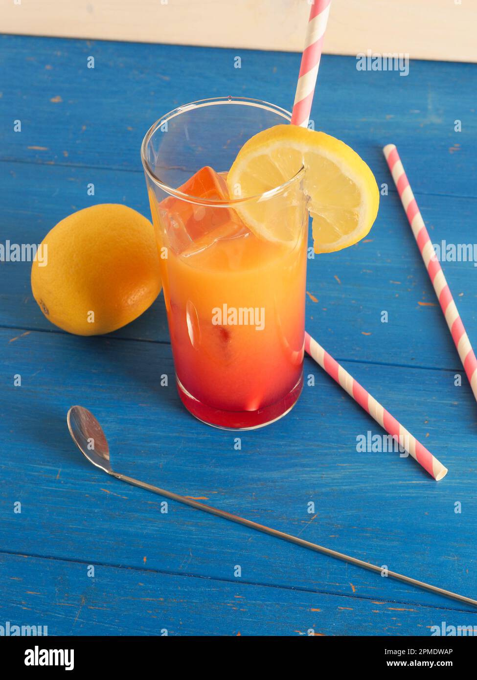 Cocktail sans alcool avec jus d'orange et de citron et sirop de grandine sur glace, savoureuse boisson d'été sur fond de bois Banque D'Images