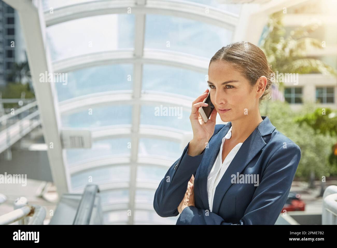 Écoute de la messagerie instantanée. une jeune femme d'affaires qui parle sur son téléphone portable tout en se tenant au sommet d'un escalier roulant. Banque D'Images