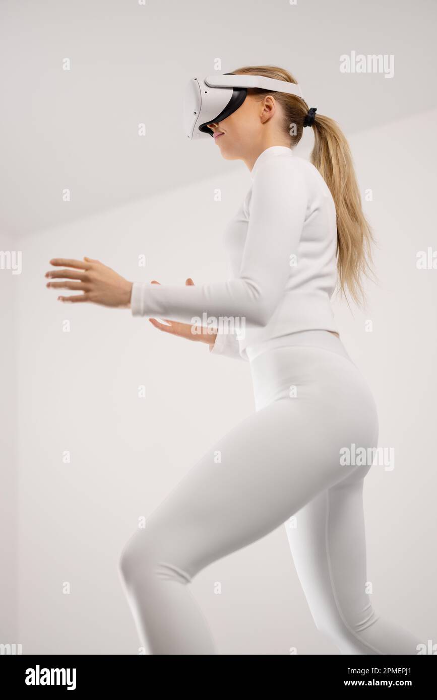 Vue en contre-plongée d'une jeune femme futuriste qui porte la technologie VR explorant la réalité virtuelle en métaverse. Propre contemporain et mi Banque D'Images