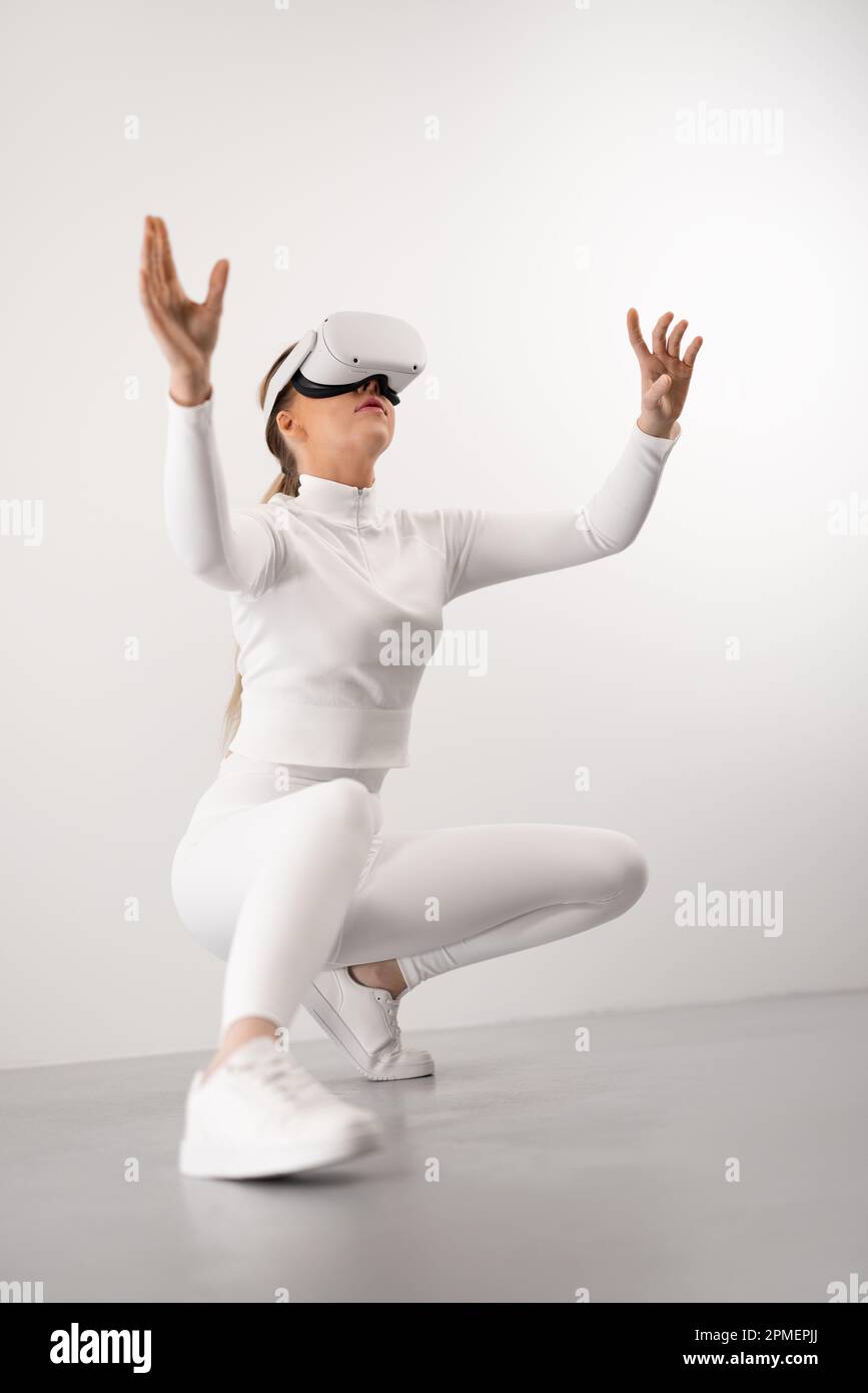 Femme futuriste et belle assise assis en utilisant la technologie VR pour explorer la réalité virtuelle en métaverse. Propre contemporain et min Banque D'Images
