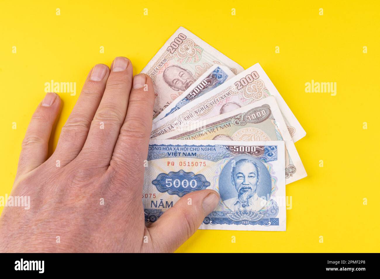 Quelques billets de Dong vietnamiens sur une surface jaune Banque D'Images