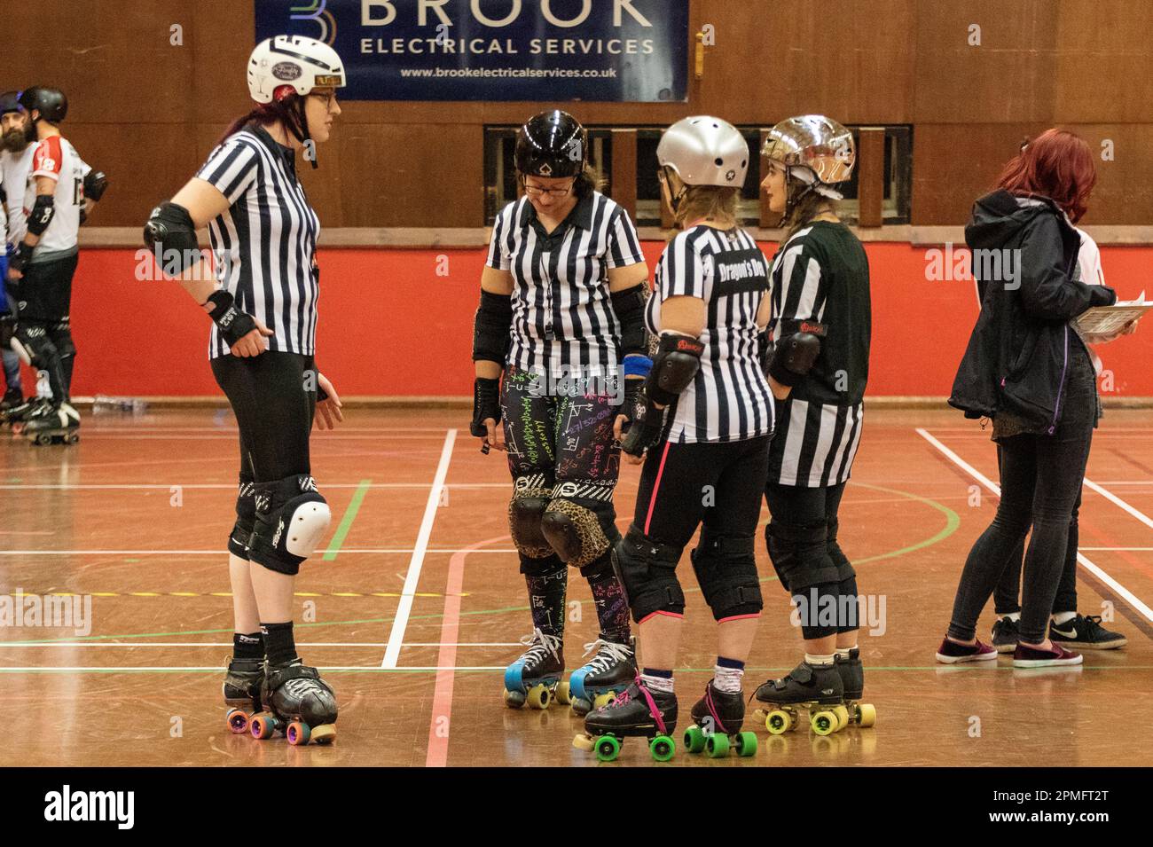 Roller derby arbitres à une ligue mixte scrimmage se rassemblent dans le centre de la piste pour échanger des vues Banque D'Images