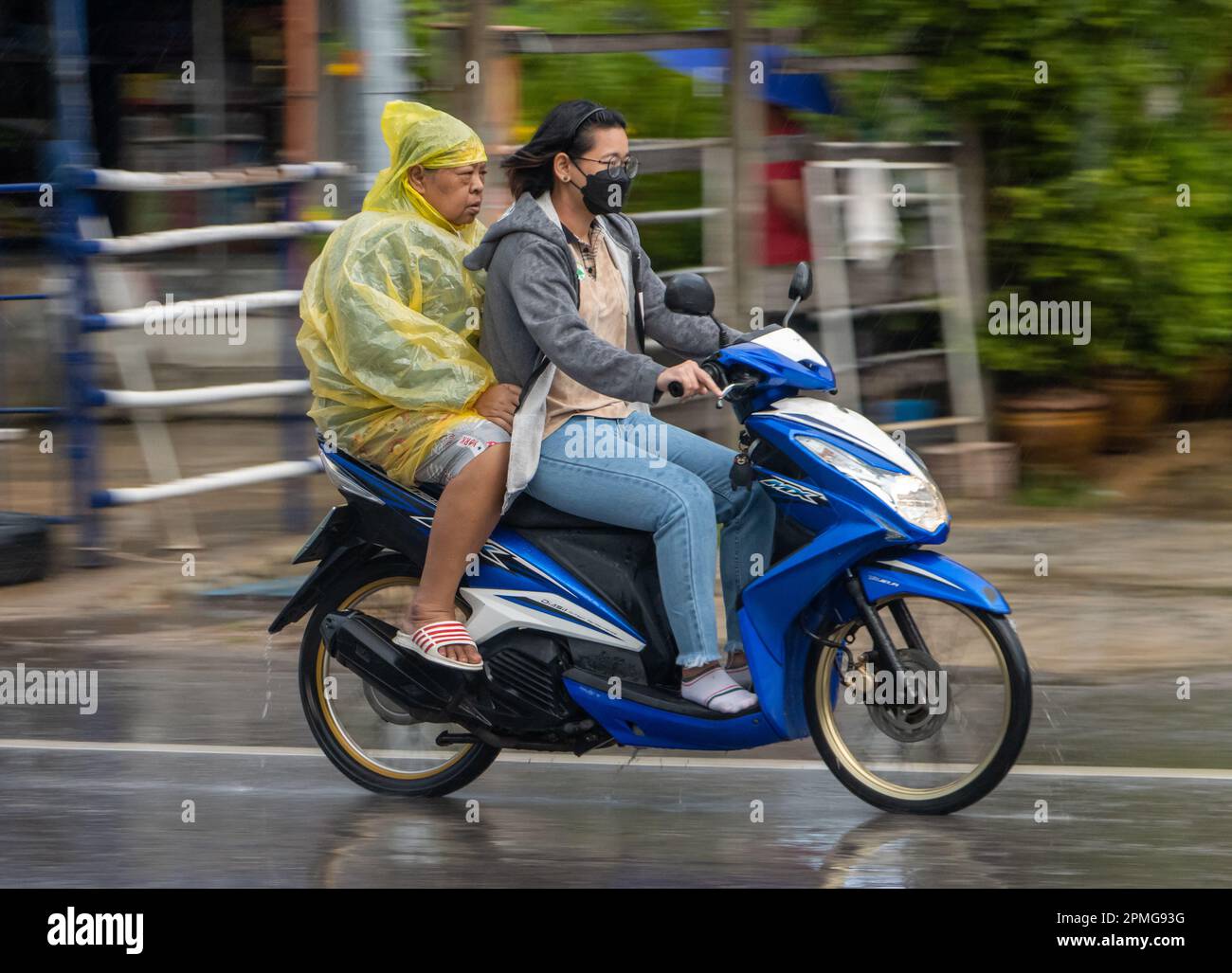SAMUT PRAKAN, THAÏLANDE, SEP 21 2022, deux femmes conduisent une moto sous la pluie Banque D'Images
