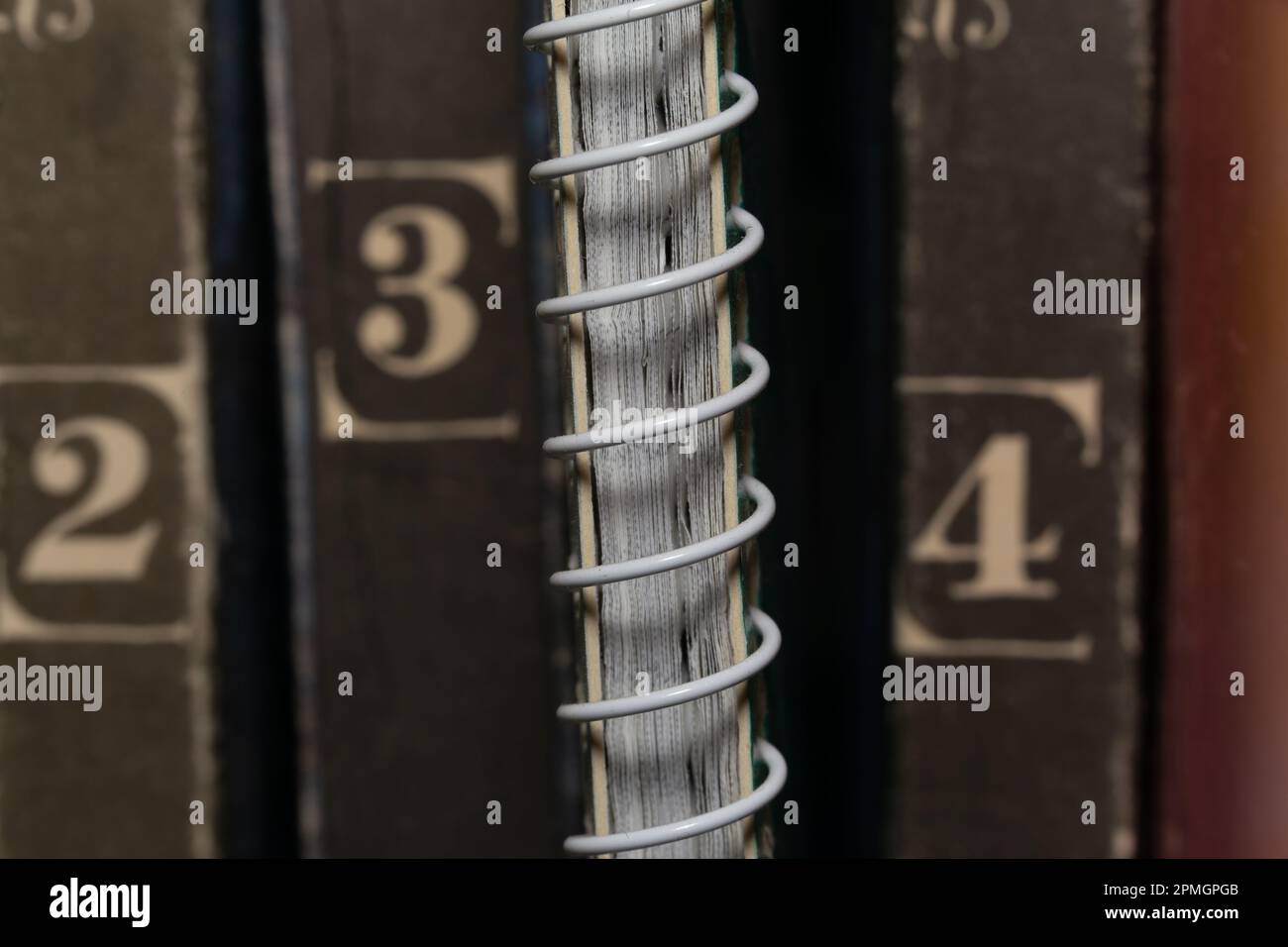 Un bloc-notes à ressort parmi les volumes de livres bruns anciens, vue macro en gros plan Banque D'Images