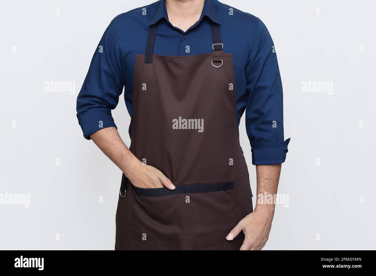Homme asiatique portant le tablier, un barista ou un chef cuisinier dans des vêtements décontractés et élégants, debout pose haute avec une main dans la poche du tablier, pas de visage Banque D'Images