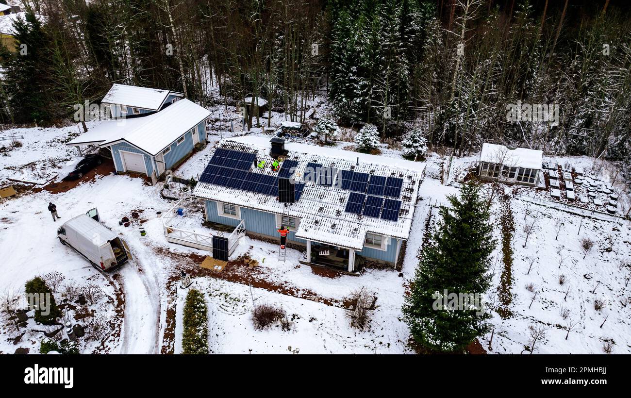 Vue aérienne travailleurs sur le dessus de la maison installer des panneaux solaires sur un toit, jour d'hiver Banque D'Images