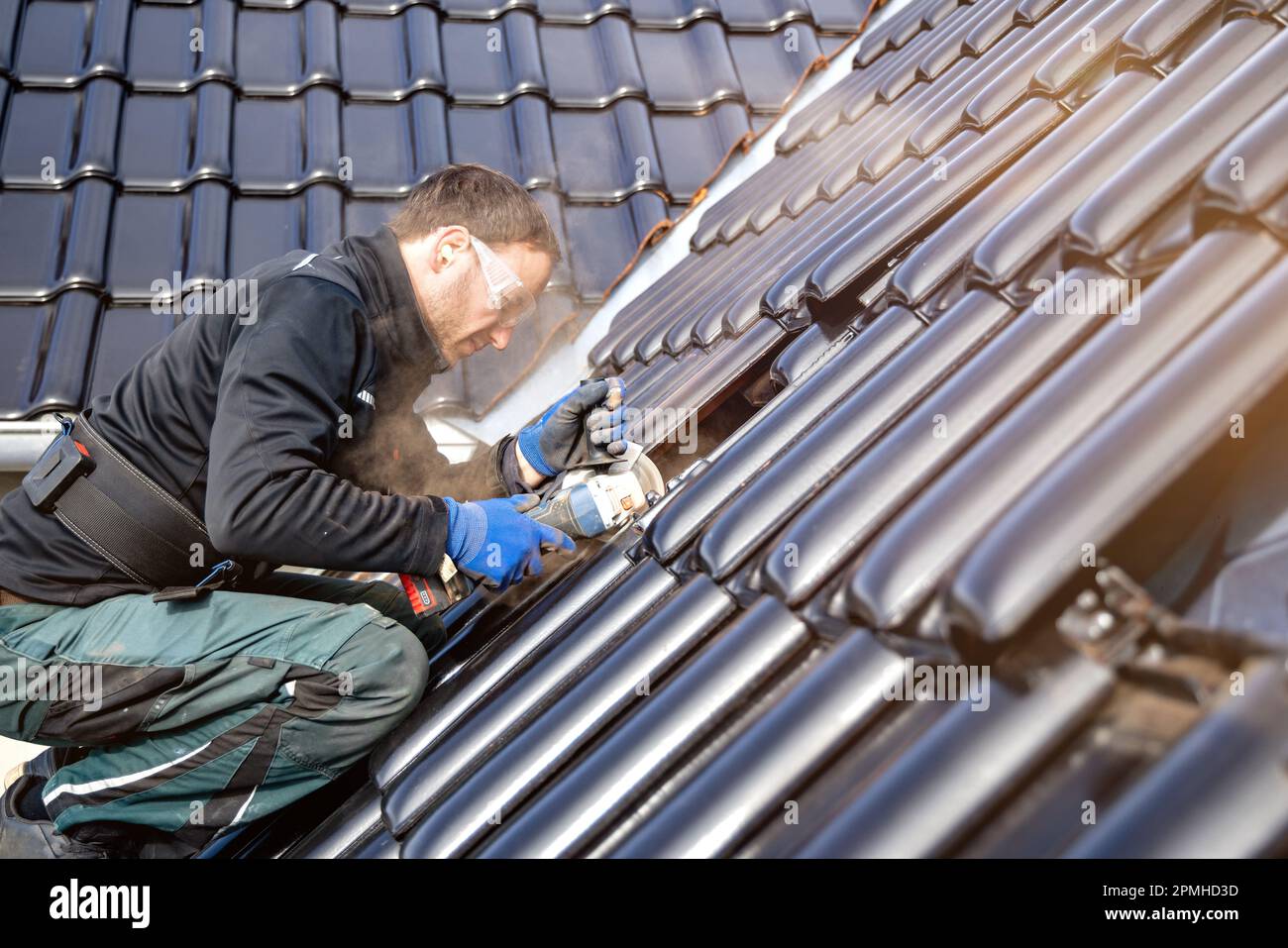 Artisan utilisant une meuleuse d'angle pour couper une tuile sur un toit Banque D'Images