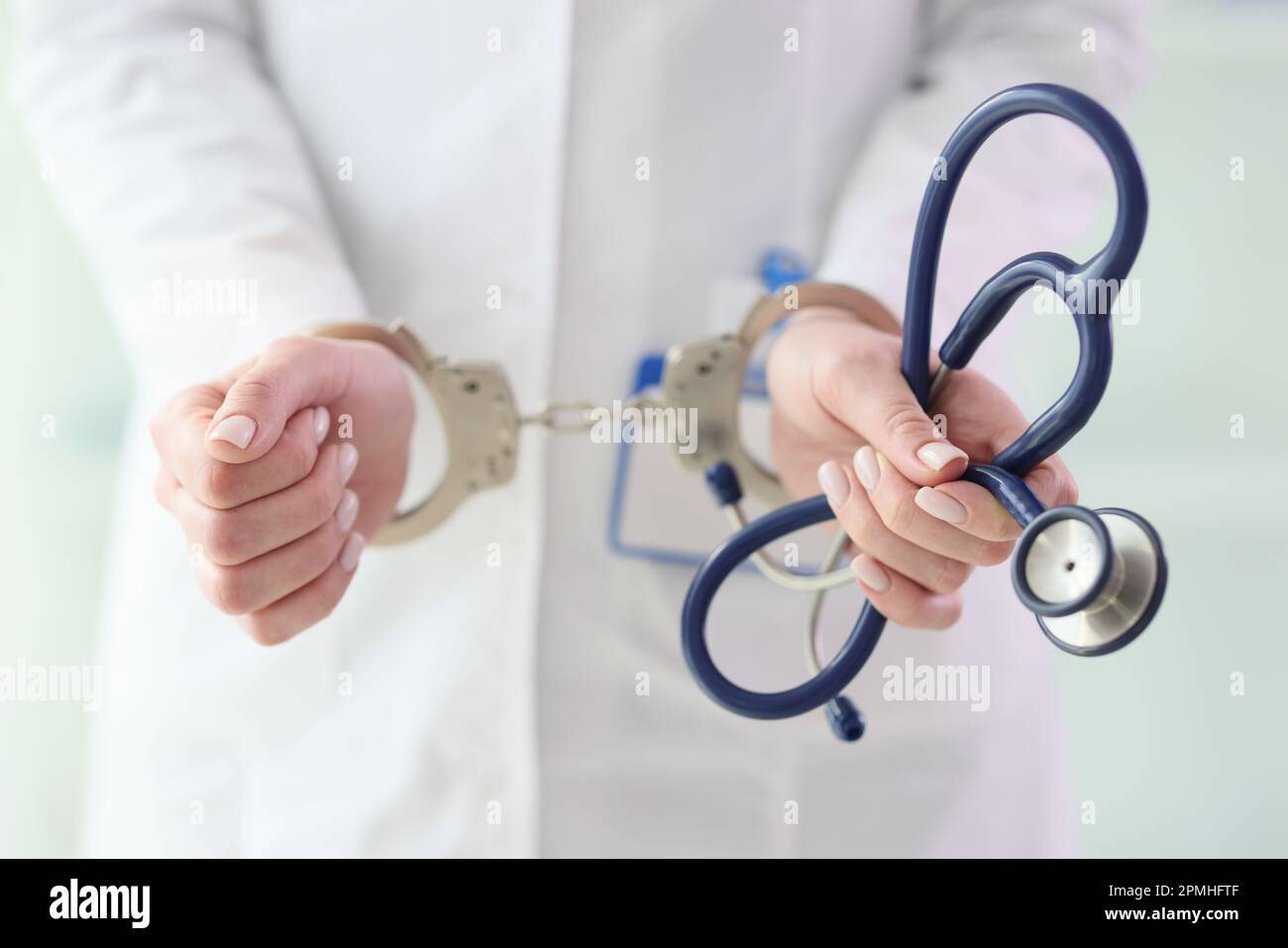 Médecin en manteau blanc avec menottes tient le stéthoscope Banque D'Images