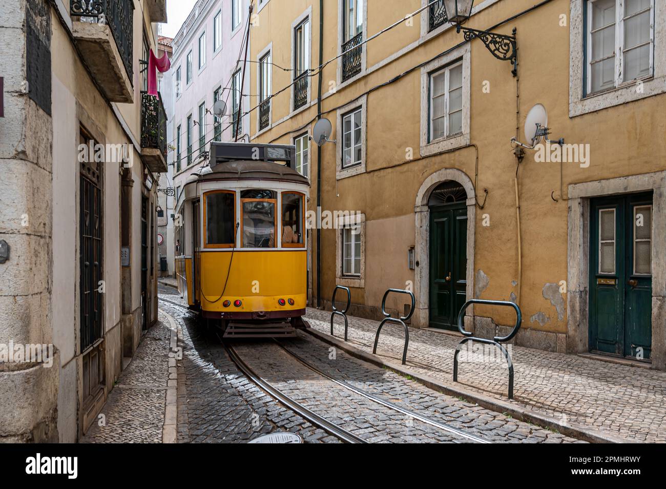 Tramway jaune rétro dans une rue étroite de Lisbonne, Portugal Banque D'Images
