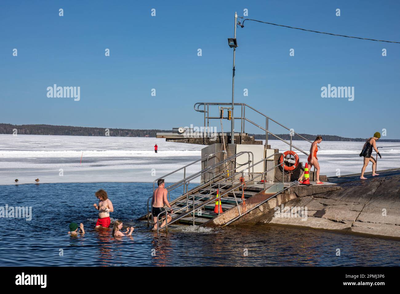Les gens nagent sur glace lors d'une journée de printemps ensoleillée au Rauhaniemi Folk Spa ou au Rauhaniemen kankylpylä à Tampere, en Finlande Banque D'Images