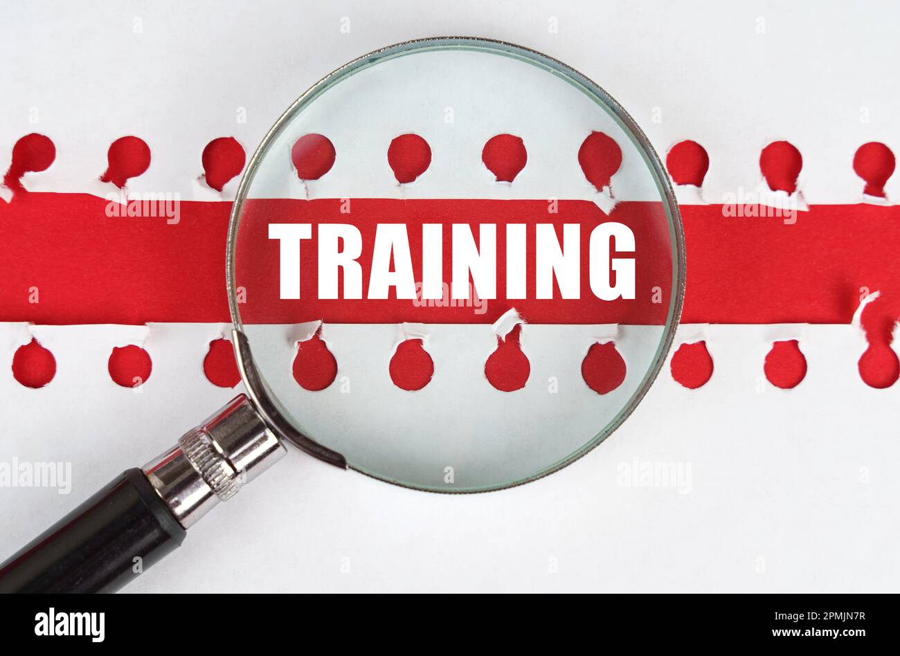 Entre deux feuilles d'un carnet sur une bande rouge avec l'inscription - entraînement, il y a une loupe. Banque D'Images