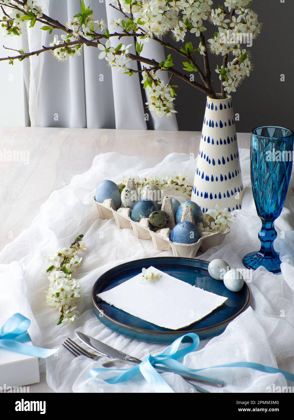 Table de Pâques festive avec fleurs, œufs peints et boîte cadeau sur fond blanc. Les nappes pastel et bleues sont élégantes. Fête de Pâques. De Banque D'Images