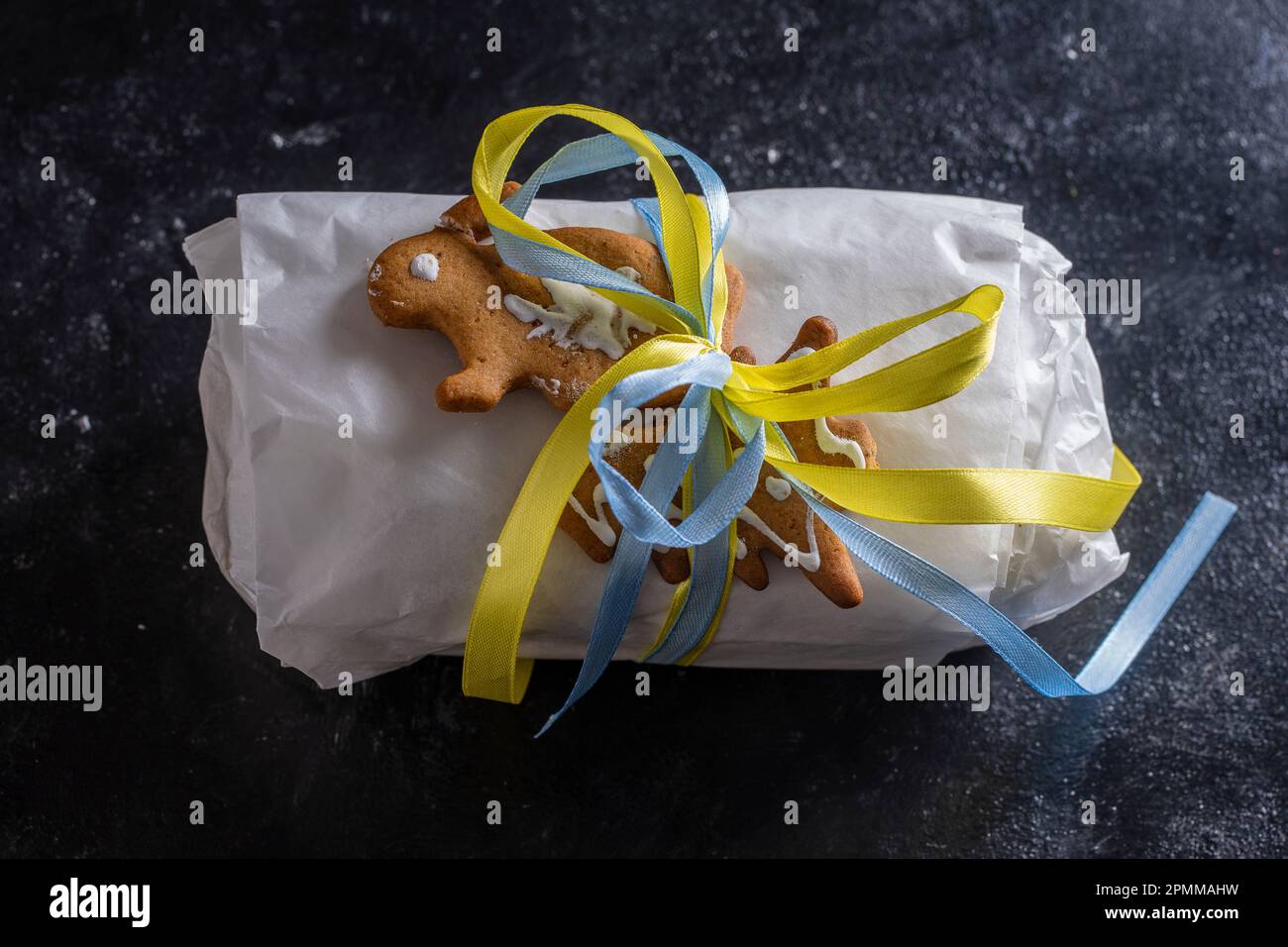 Noël en papier blanc avec ruban jaune et bleu pour un cadeau de Noël, pain allemand traditionnel pour un dessert de pâtisserie festif. Clos Banque D'Images