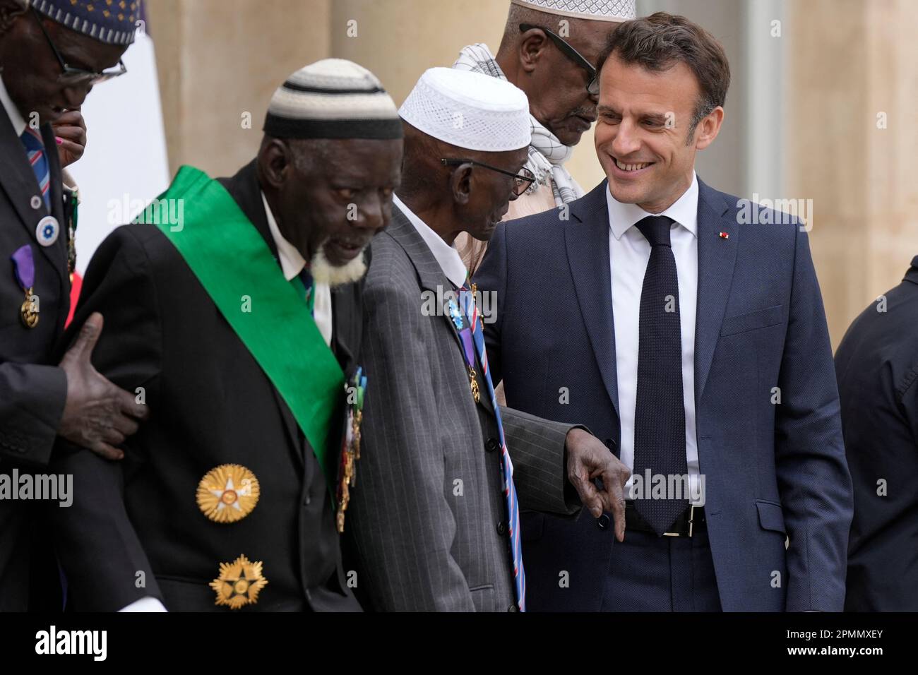 Paris, France. 14th avril 2023. Le président français Emmanuel Macron, à droite, s'entretient avec les anciens combattants sénégalais après leur rencontre, vendredi, à 14 avril 2023, à l'Elysée à Paris. Certains des derniers survivants en France d'un corps d'infanterie de l'époque coloniale qui a recruté des dizaines de milliers de soldats africains pour combattre dans les guerres françaises à travers le monde pourront vivre leurs derniers jours avec des membres de la famille de retour en Afrique après un demi-tour du gouvernement français plus tôt année sur leurs droits à pension. Photo de Lewis Joly/Pool/ABACAPRESS.COM crédit: Abaca Press/Alay Live News Banque D'Images