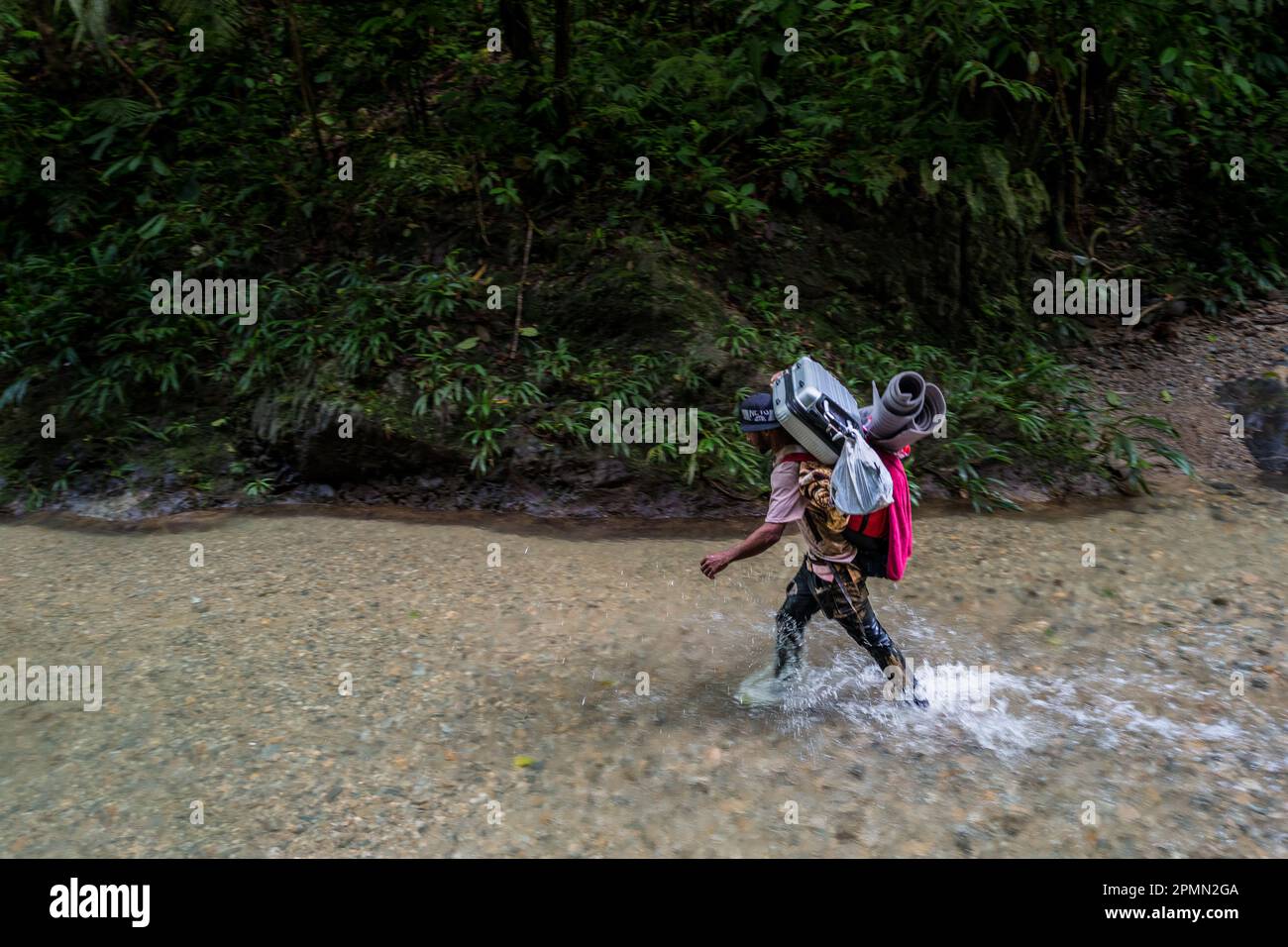 Un migrant vénézuélien traverse la rivière dans la jungle sauvage et dangereuse du fossé Darién entre la Colombie et Panamá. Banque D'Images