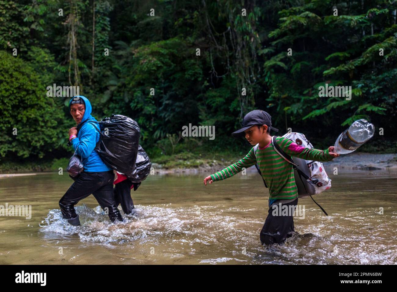 Une famille équatorienne de migrants traverse le fleuve dans la jungle sauvage et dangereuse du fossé Darién entre la Colombie et Panamá. Banque D'Images