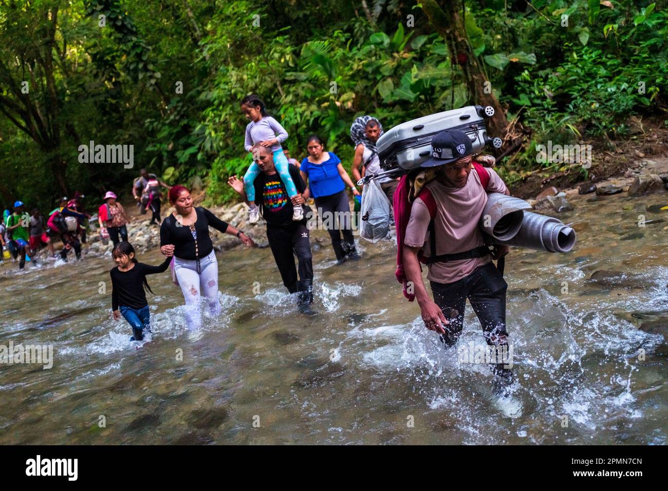 Des migrants, principalement originaires d'Equateur, d'Haïti et du Nigeria, traversent la rivière dans la jungle dangereuse du fossé Darién entre la Colombie et Panamá. Banque D'Images