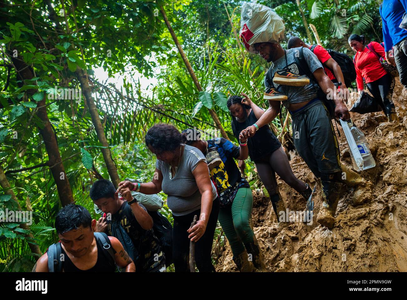 Les migrants haïtiens grimpent sur un sentier boueux à flanc de colline dans la jungle sauvage et dangereuse du fossé Darién entre la Colombie et Panamá. Banque D'Images