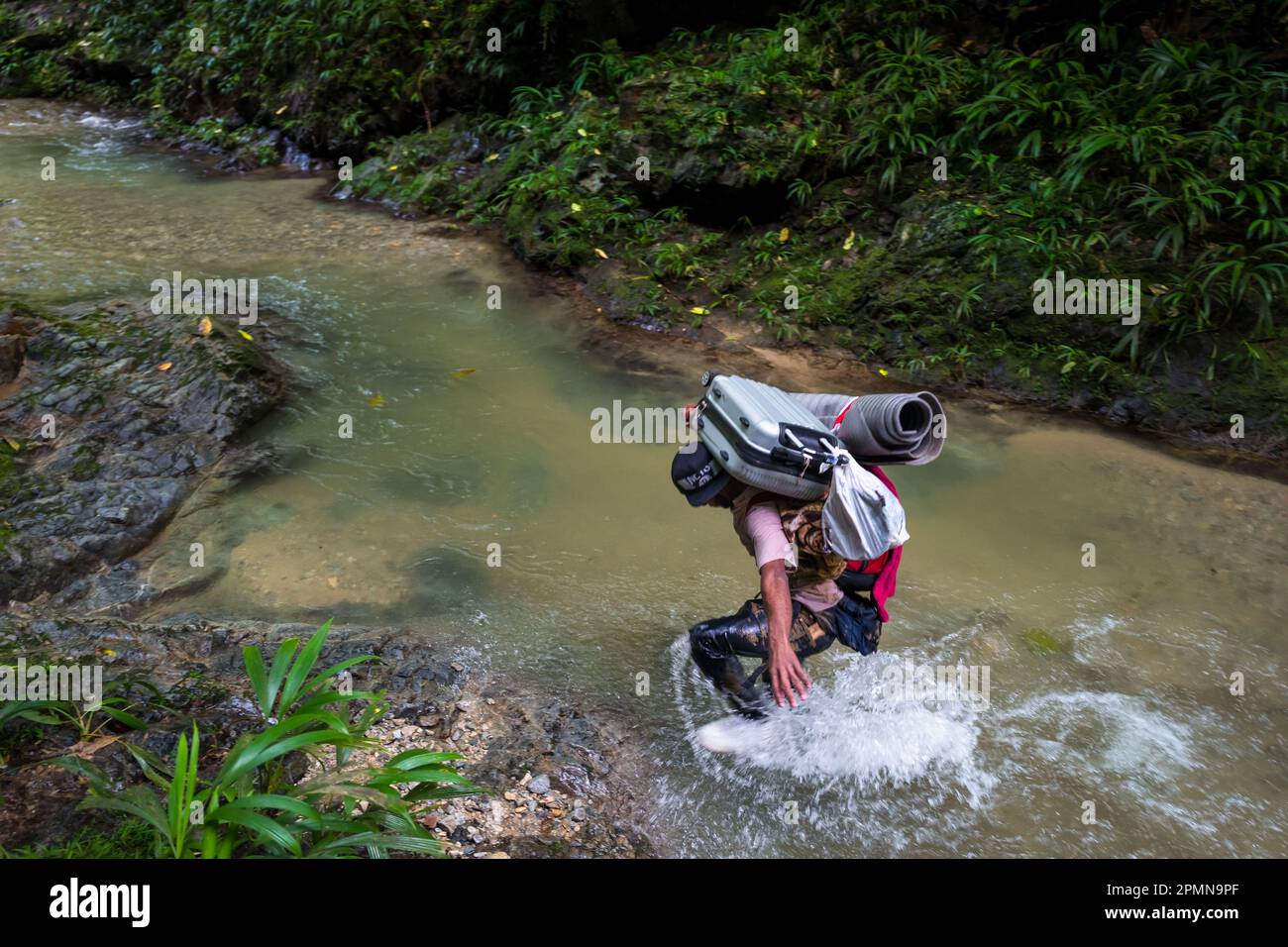 Un migrant vénézuélien traverse la rivière dans la jungle sauvage et dangereuse du fossé Darién entre la Colombie et Panamá. Banque D'Images