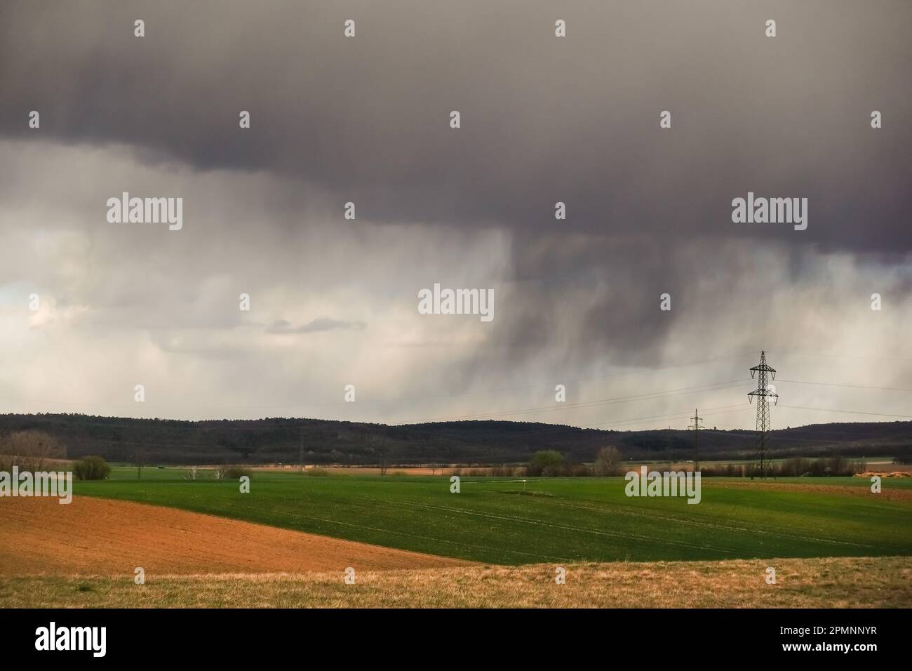 nuage de pluie dense foncé avec pluie sur différents champs et une forêt au printemps Banque D'Images