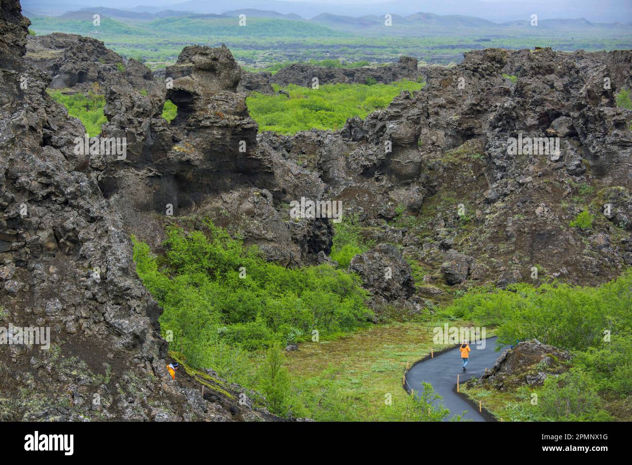 Randonneur marche devant les formations de lave de Dimmuborgir en Islande ; Islande Banque D'Images