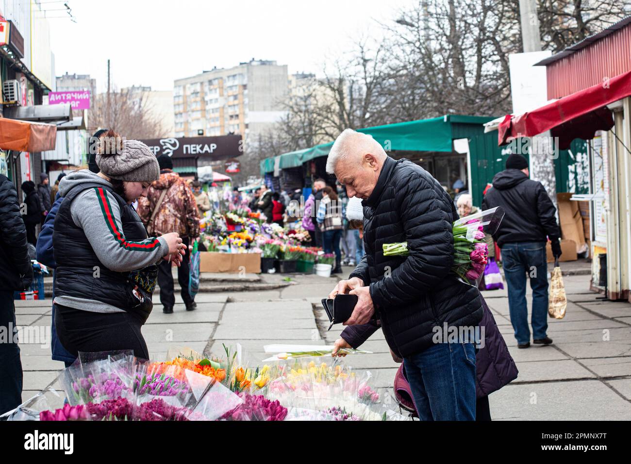 Le monsieur adulte achète un bouquet de tulipes sur le marché de Kiev le 8th mars 2023, car de nombreux hommes continuent de payer le respect à leurs dames, les mères. Banque D'Images