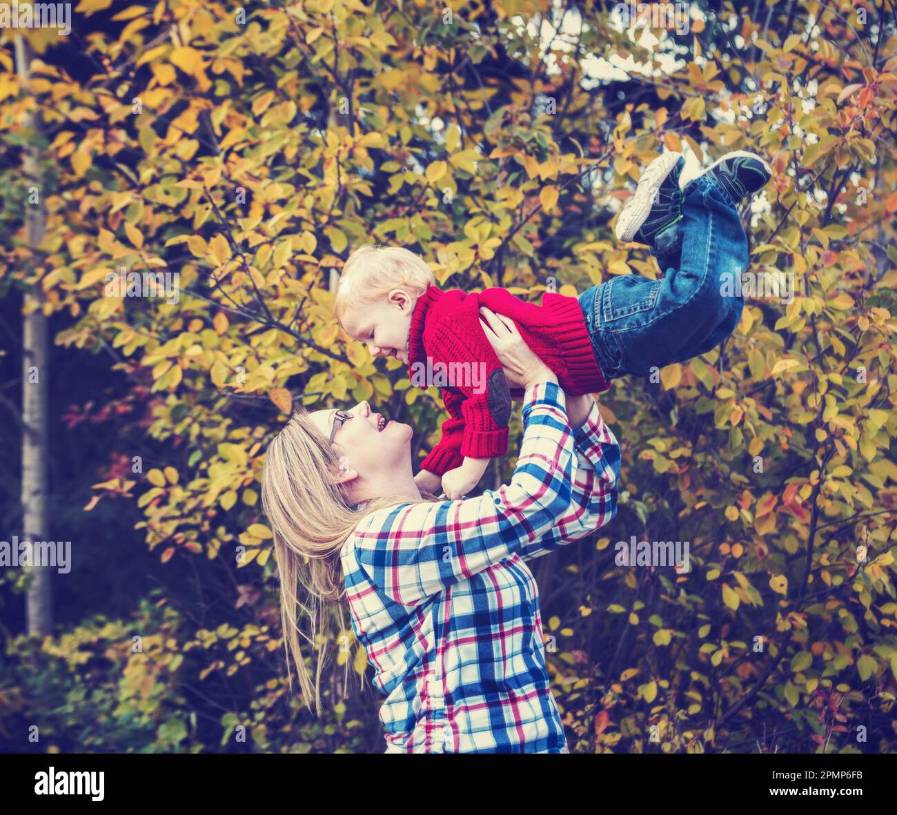 Mère joue à l'extérieur avec son jeune fils, le soulevant dans les airs; Edmonton, Alberta, Canada Banque D'Images