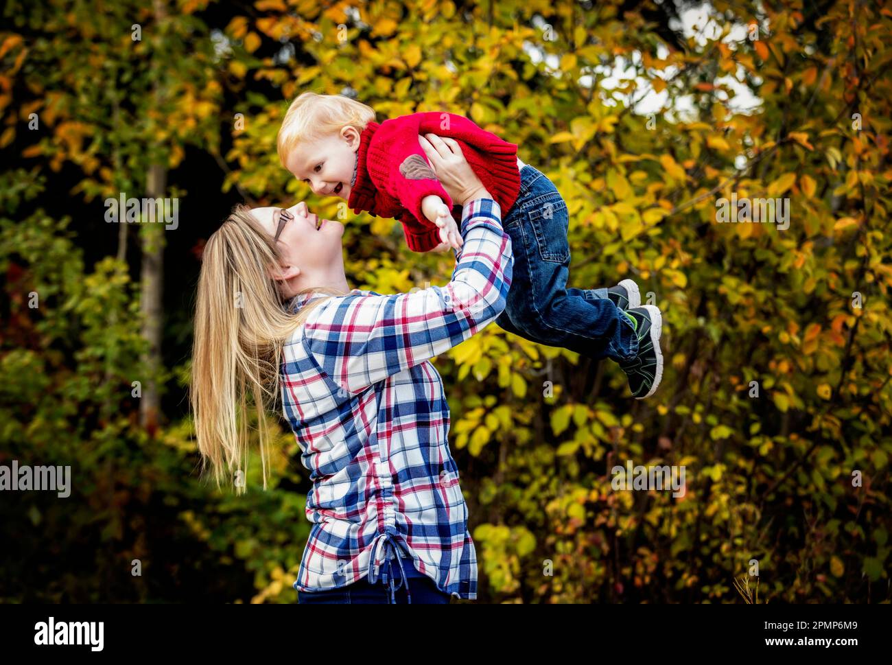 Mère joue à l'extérieur avec son jeune fils, le soulevant dans les airs; Edmonton, Alberta, Canada Banque D'Images