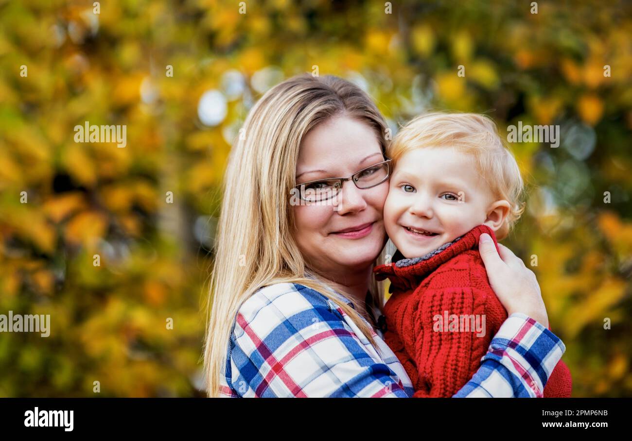 Portrait extérieur d'une mère tenant un jeune fils à proximité, dans un parc en automne; Edmonton, Alberta, Canada Banque D'Images