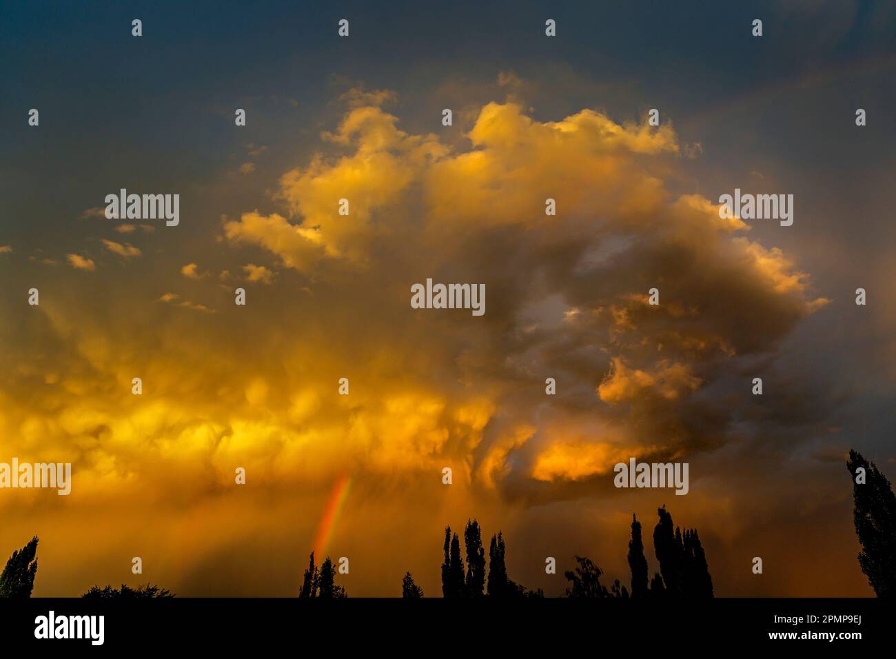 Des nuages orange spectaculaires au coucher du soleil avec un ciel bleu et arc-en-ciel au-dessus; Calgary, Alberta, Canada Banque D'Images