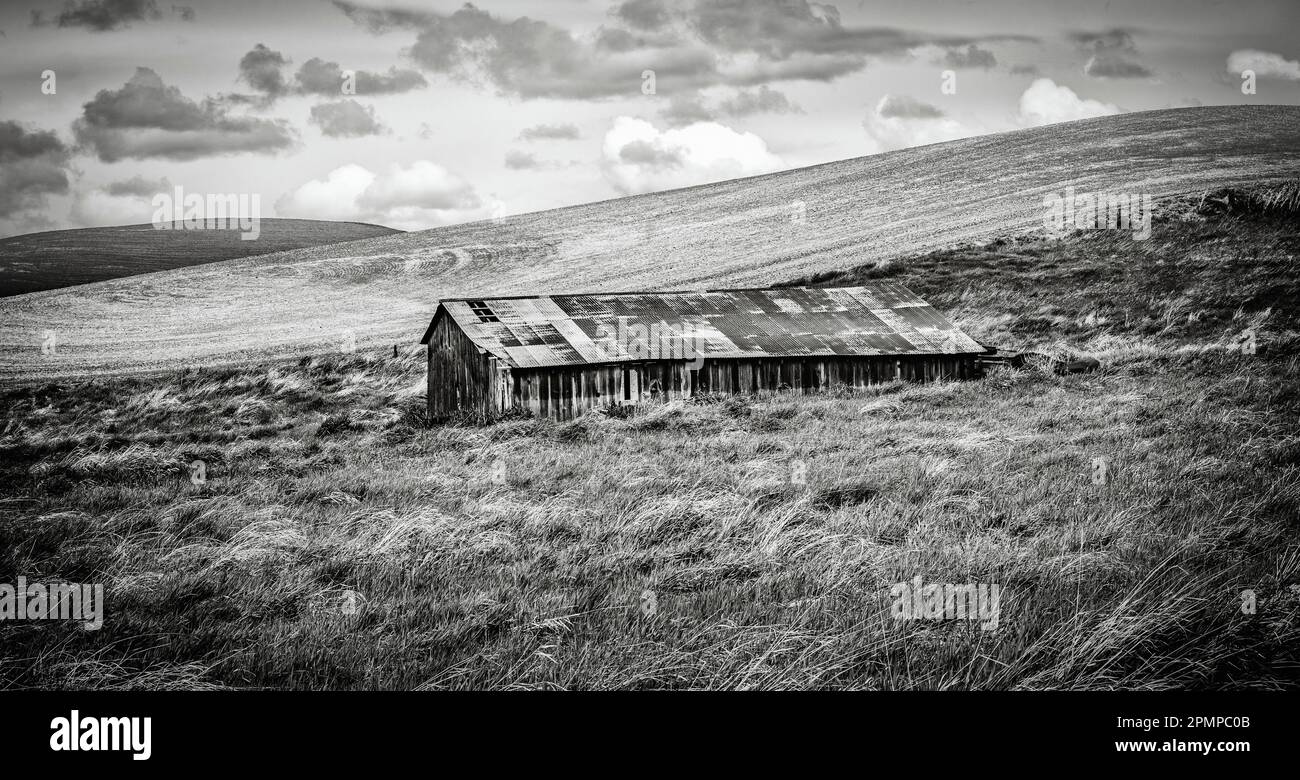 Image en noir et blanc d'une ancienne grange abandonnée effrayante sous des nuages météorologiques menaçants dans l'est de Washington, États-Unis Banque D'Images