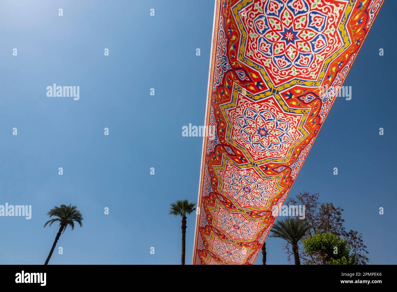 Tissu égyptien coloré contre un ciel bleu saisissant et des palmiers éloignés Banque D'Images