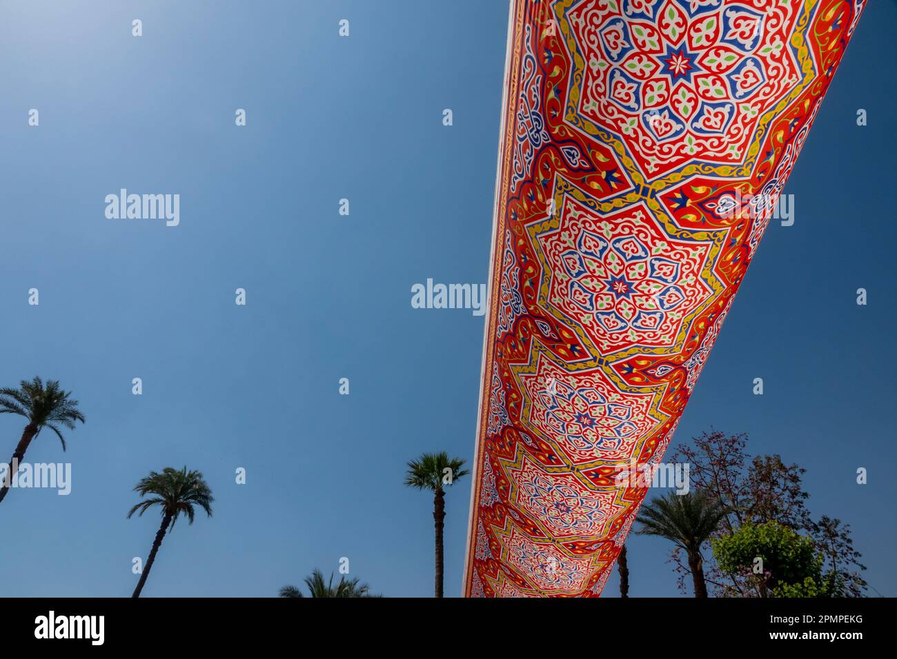 Tissu égyptien coloré contre un ciel bleu saisissant et des palmiers éloignés Banque D'Images