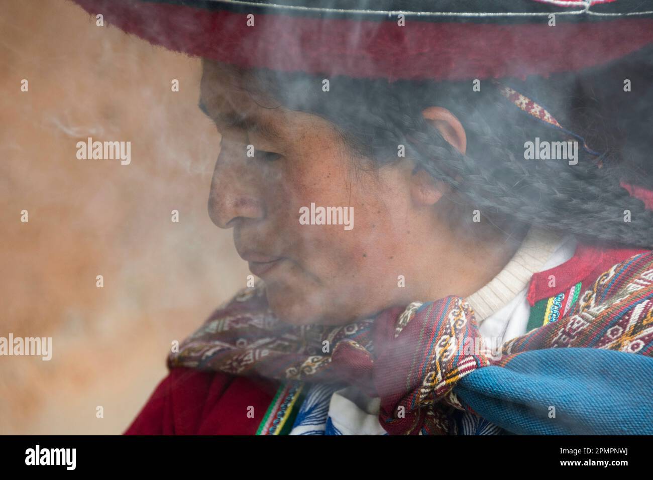 Femme péruvienne brûlant des plantes dans le cadre de l'extraction de colorants au Centre pour les textiles traditionnels ; district de Chinchero, Pérou Banque D'Images
