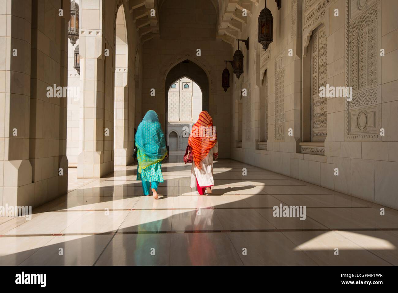 Deux femmes habillées traditionnellement marchant dans un couloir de la Grande Mosquée du Sultan Qaboos ; Muscat, Oman Banque D'Images