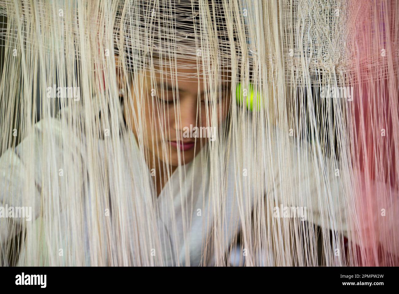 Femme tissant derrière des brins de fil fin à Ock Pop Tock, un centre d'artisanat vivant ; Luang Prabang, Laos Banque D'Images