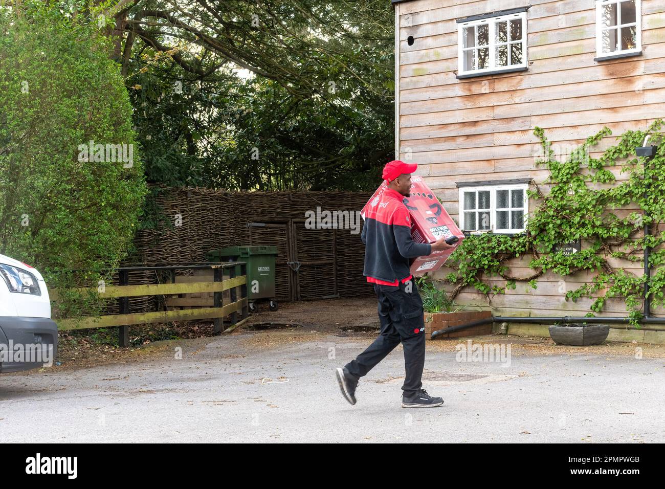 Chauffeur de messagerie DPD livrant un gros colis à une propriété, Angleterre, Royaume-Uni Banque D'Images